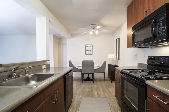 Classic Package kitchen with black appliances, dark grey laminate countertops, cherry cabinetry, and hard surface flooring