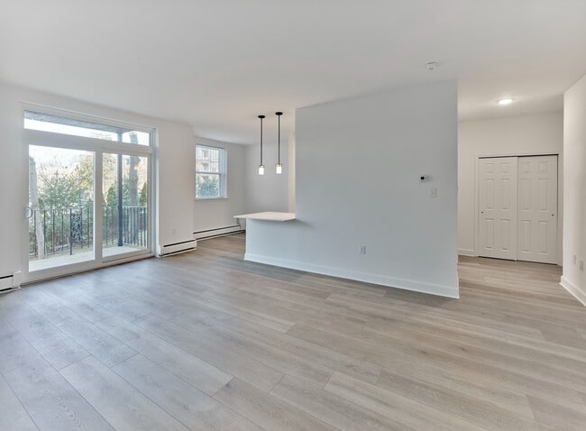 Sala de estar y comedor abiertos con luz natural y acceso al balcón en Crestwood Apartments en Wayne, PA - Crestwood