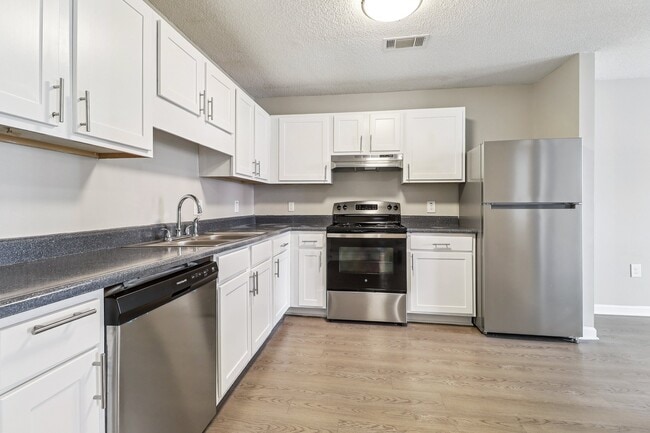 Enjoy bright, modern kitchens featuring white cabinetry and stainless steel appliances, professionally operated by Highlands Vista Group. - Avalon Place