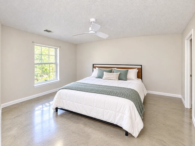 Primary bedroom with sealed concrete floors and celing fan.