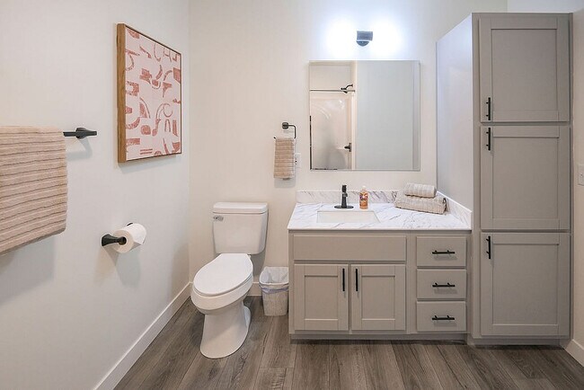 Baño elegante con accesorios modernos, iluminación acogedora y elegantes gabinetes. Cuenta con una encimera de mármol y arte mural contemporáneo.
