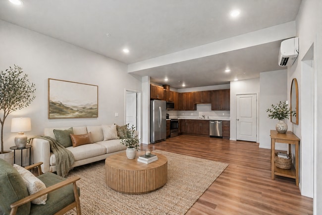Chic open-concept living area featuring modern kitchen with dark wood cabinets, plank flooring, and stainless steel appliances.