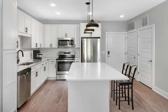 Modern kitchen with white cabinetry, white quartz countertops, and stainless steel appliances
