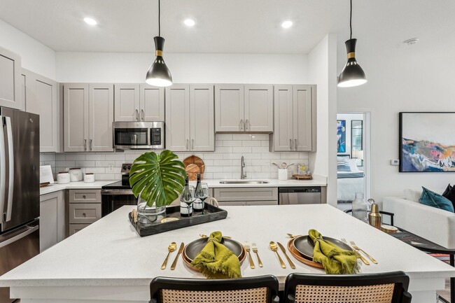 A modern kitchen with a dining table set for two. - Tapestry University Park Apartments
