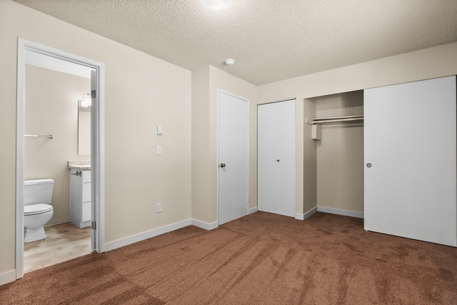 Carpeted bedroom with large closet and access to ensuite bathroom. - Crossroads at Meridian Apartments