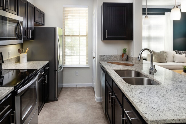 Kitchen with espresso cabinetry, granite countertops, and stainless steel appliances - Avalon Frisco at Main
