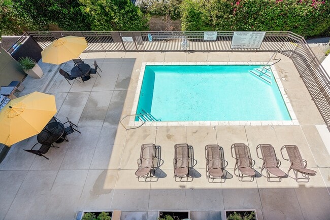 Área de piscina privada con tumbonas y mesas de patio con sombrillas