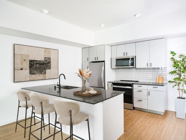 Kitchen with a spacious island, bar seating, and stainless steel appliances set within a bright layout designed for cooking and daily connection.