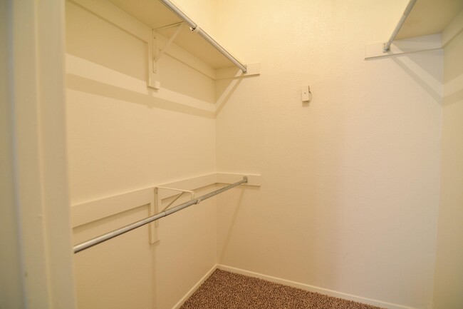 Un amplio vestidor con varios estantes y barras para colgar ropa. - Wildflower