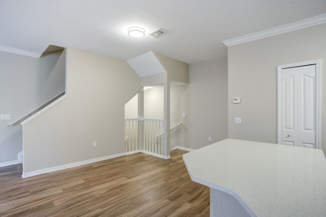 Image of the living room area with wood-style plank style floors a staircase leading upstairs. - Amara at Metro West