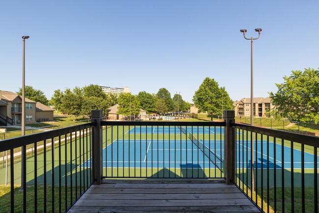 Balcony of an apartment unit at The Lakes, with a view of the community tennis courts and outdoor surroundings.