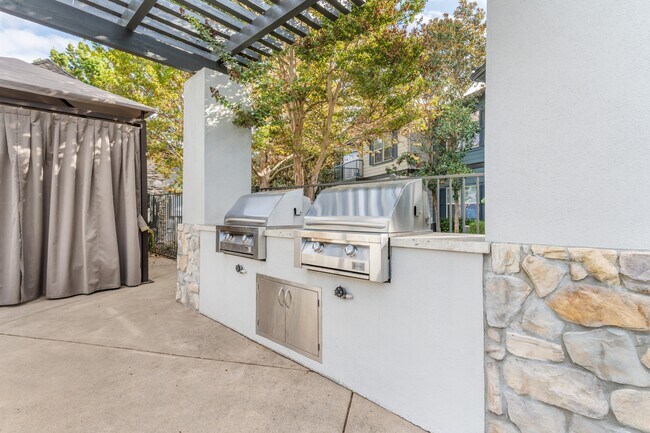 We offer two stainless steel barbecue grills on the side of a patio - Harvest Park Apartment Homes