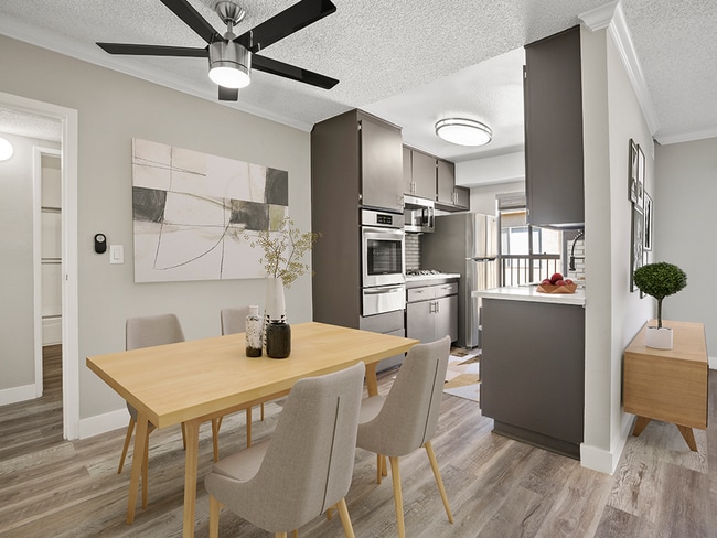 Hardwood floored dining room with view of modern-styled kitchen. - Tilden II Apartments