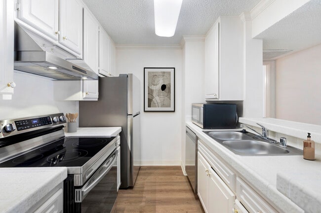 Classic Package II kitchen with white tile countertops, white cabinetry, stainless steel appliances, and hard surface flooring