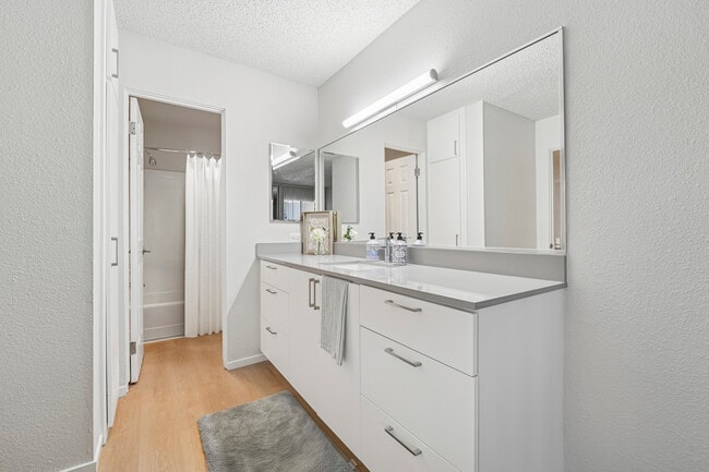 Renovated Package I bath with white cabinetry, grey quartz countertops, and hard surface flooring