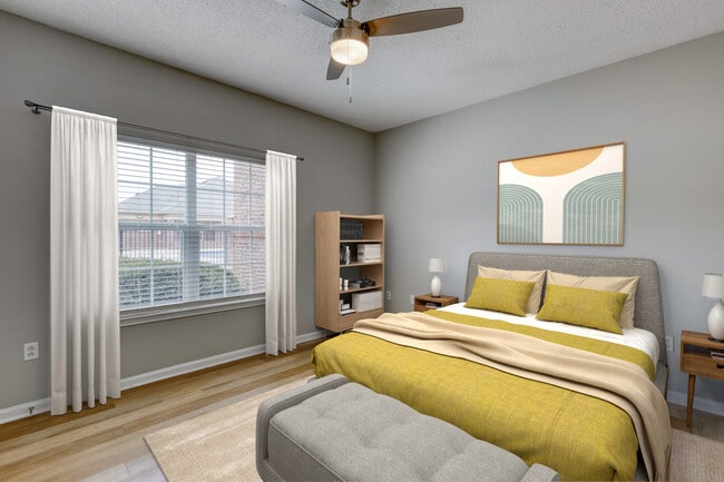 Open-concept dining area at Dunwoody Place featuring a small dining table, light wood flooring, neutral gray walls, and a kitchen pass-through with bar seating in an income-restricted apartment in Huntsville, Alabama.