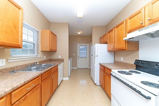 Kitchen with white appliances, wooden cabinetry, and generous counterspace