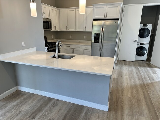 Tasteful galley kitchen w/quartz breakfast bar, SS appliances & wood cabinets - 271 Millburn Ave Unit 2D