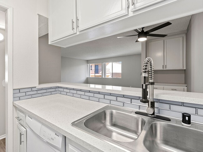 White tiled kitchen with stainless steel farmhouse style sink.