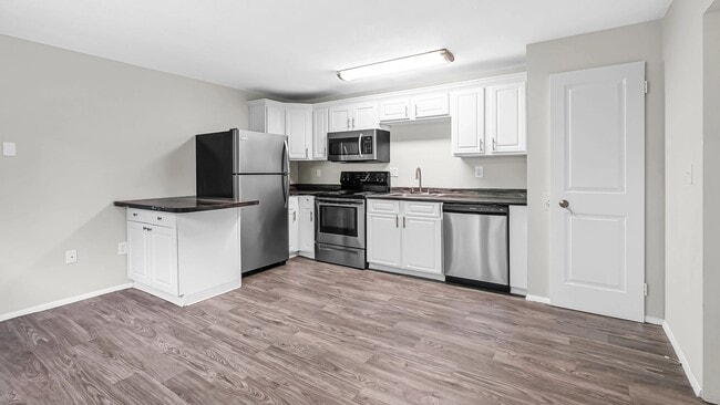 Experience harmonious living with an open-concept kitchen and living room both graced by stunning grey wood-style flooring.