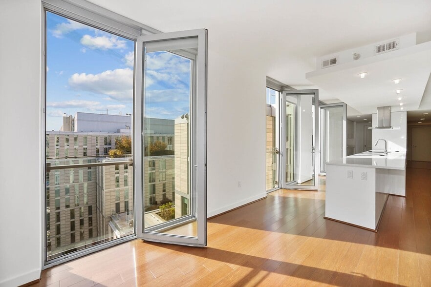 Bright and contemporary apartment with expansive glass doors, offering stunning urban views and a minimalist kitchen design.