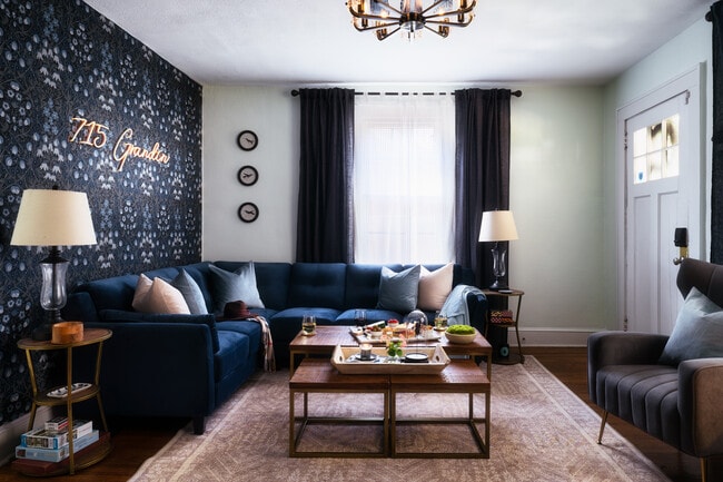 A spacious living room with a navy-blue sectional, bold accent wall, and elegant lighting