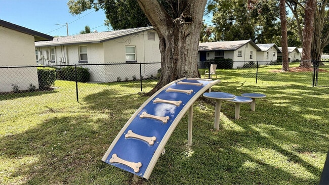 Inviting pet-friendly outdoor space featuring charming agility equipment, shaded by lush trees, nestled in a serene residential setting. - Waterside Village