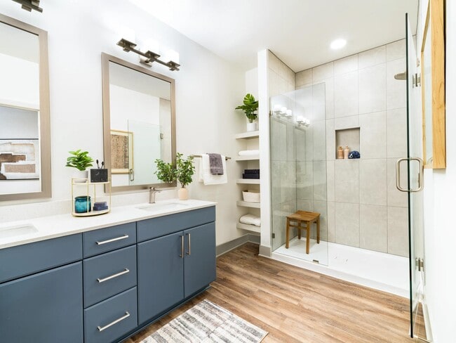 A refined primary bath with a glass-enclosed shower, open shelving, and clean-lined finishes that support a calm, everyday routine.