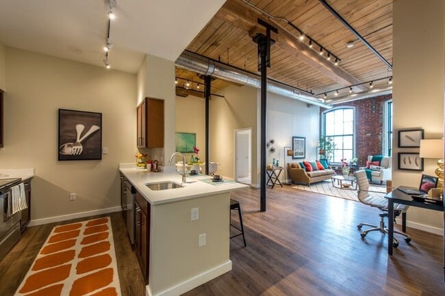 Apartamento tipo loft con paredes de ladrillo visto, techos altos y grandes ventanales.