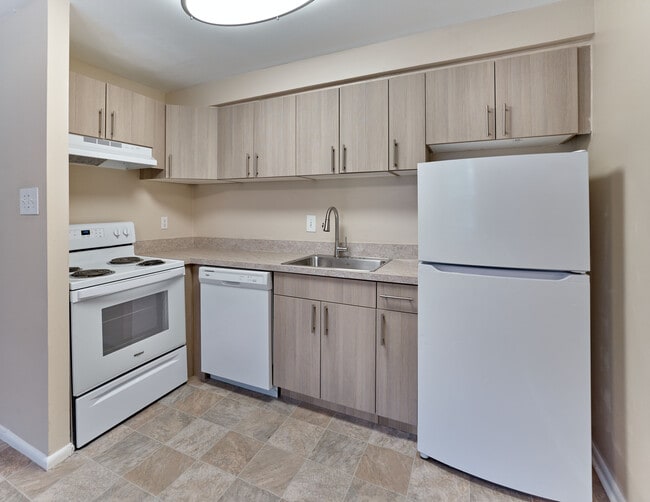 Spacious updated kitchen featuring sleek white appliances, wood-tone cabinetry, and a modern layout at Maple Terrace Apartments in Maple Shade, NJ.