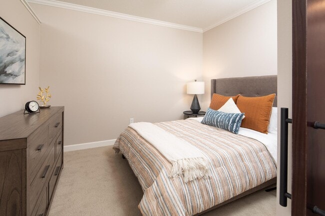 View of model bedroom with bed and dresser at The Whitley.