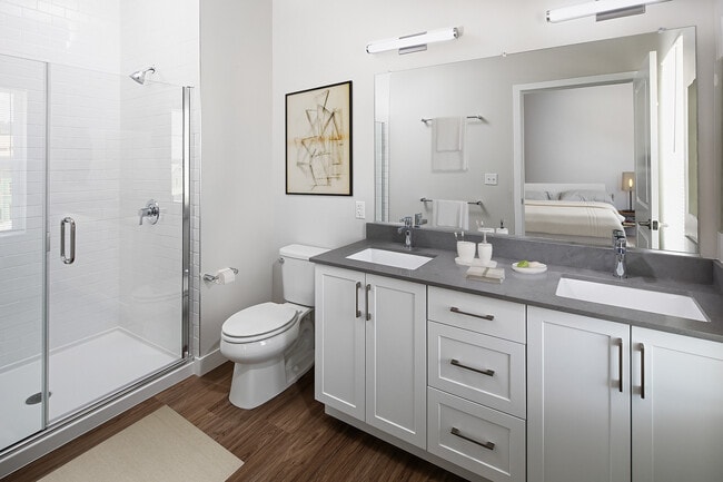 Phase II Renovated Package I townhome bath with grey quartz countertops, white cabinetry, and hard surface flooring