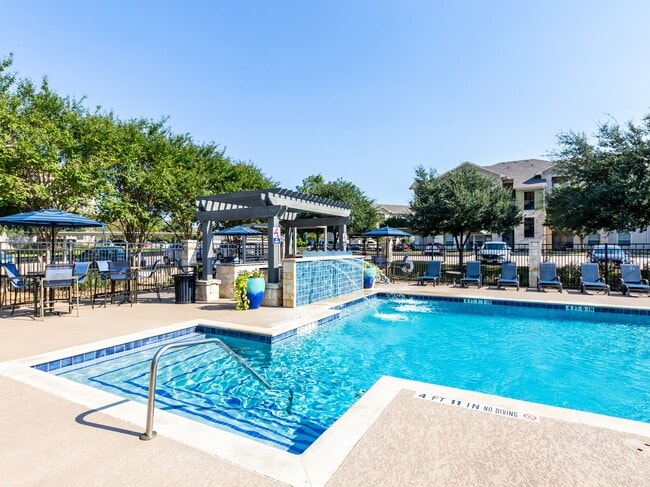 Lujosa terraza de la piscina con una serena fuente de agua y asientos de salón - Alister Oak Hill Apartamentos