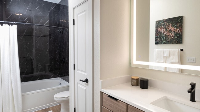 Baño del apartamento con piso estilo madera y espejo de tocador LED.