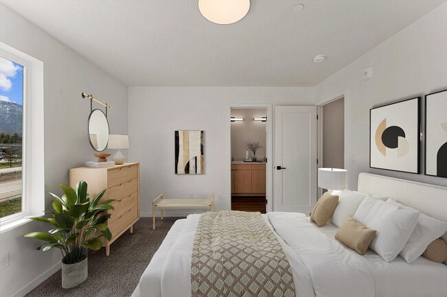 Bright and inviting bedroom with modern decor, featuring a cozy bed, stylish artwork, and a scenic window view.