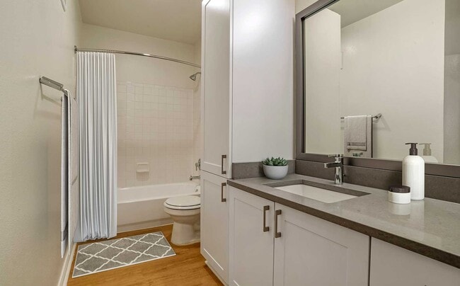 Renovated Package IV bath with white cabinetry, grey quartz countertops, and hard surface plank flooring