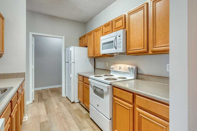 Galley kitchen with wood cabinets, laminate countertops, white appliances, electric range, and built in microwave