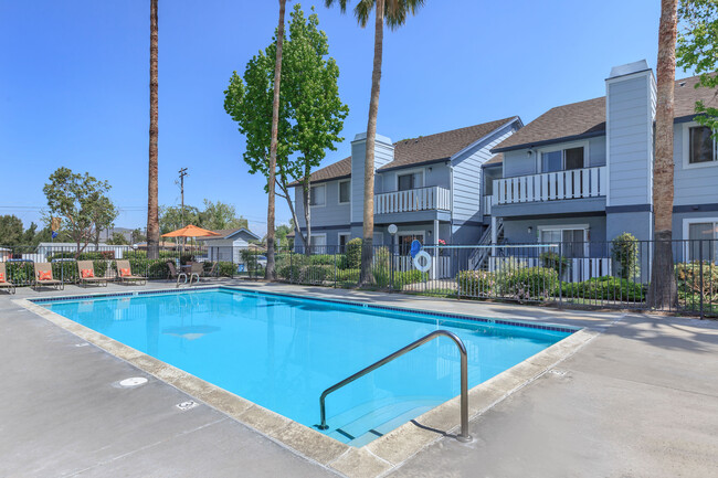 Image of the community swimming pool and welcoming lounge chairs in the background. - Camden Park Apartments