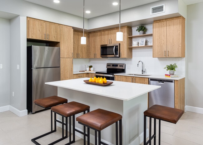 Open concept kitchen with quartz countertop, island, stainless steel appliances and tile backsplash