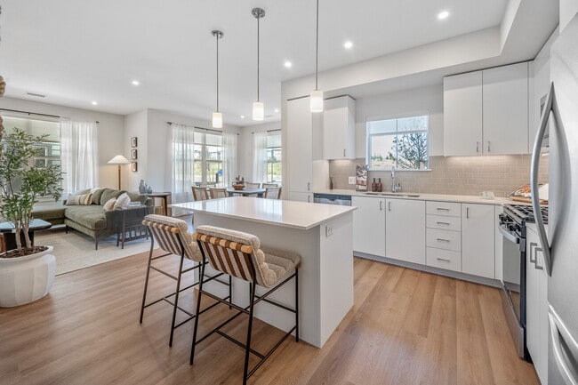 Finish Package I kitchen with stainless steel appliances, white cabinetry, grey tile backsplash, white quartz countertops, and hard surface flooring