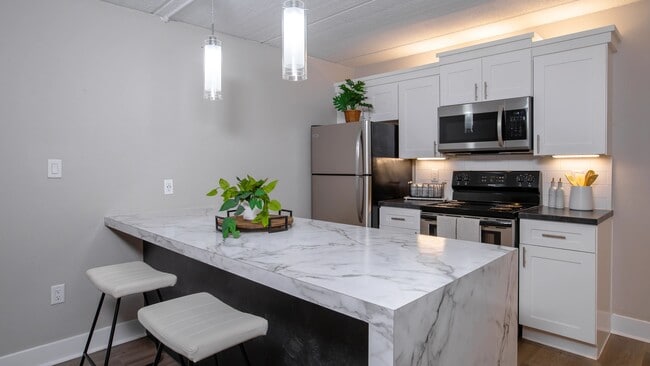 Our kitchens feature a spacious marble-style breakfast bar, stainless steel appliances, and elegant pendant lighting.