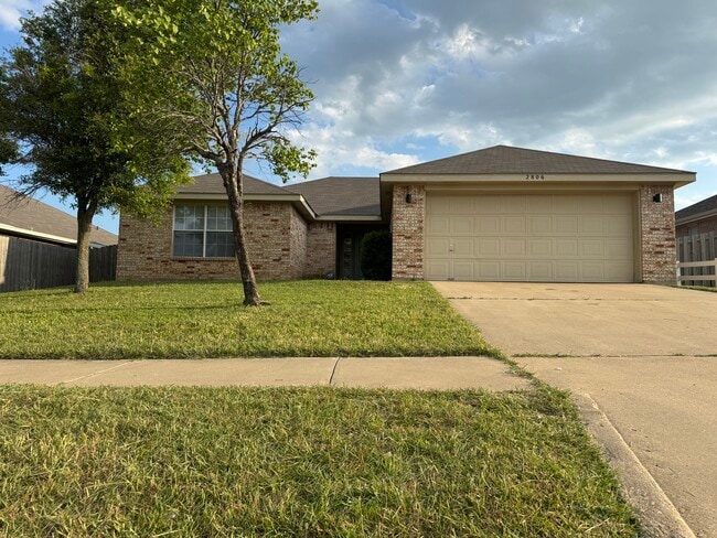 Classic brick façade, mature trees, and a two-car garage create solid curb appeal. - 2806 Maria Dr House