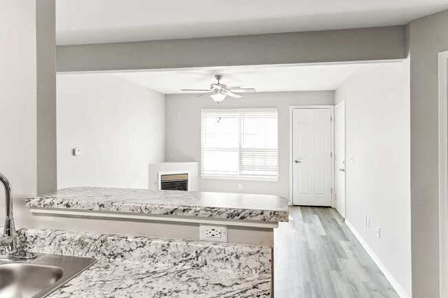 Kitchen with granite countertops, black appliances, white cabinetry, and open breakfast bar overlooking living area