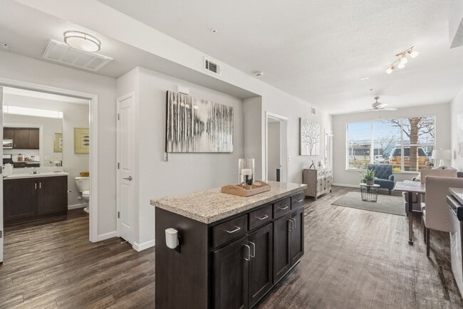 Aspire Apartments Tracy California A modern kitchen with dark wood cabinets and a granite countertop.