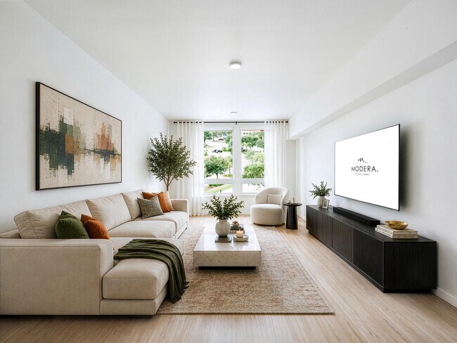 Bright living room with clean-lined furnishings, large windows, and an open layout that brings in natural light and connects to the surrounding neighborhood.