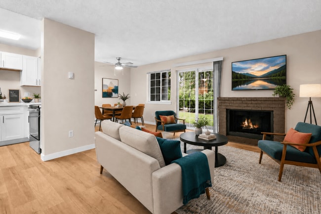 Un espacio habitable cálido y acogedor con una chimenea confortable, acceso directo al patio y una distribución abierta que conecta la sala de estar, el comedor y la cocina. - Crossroads at Meridian Apartments