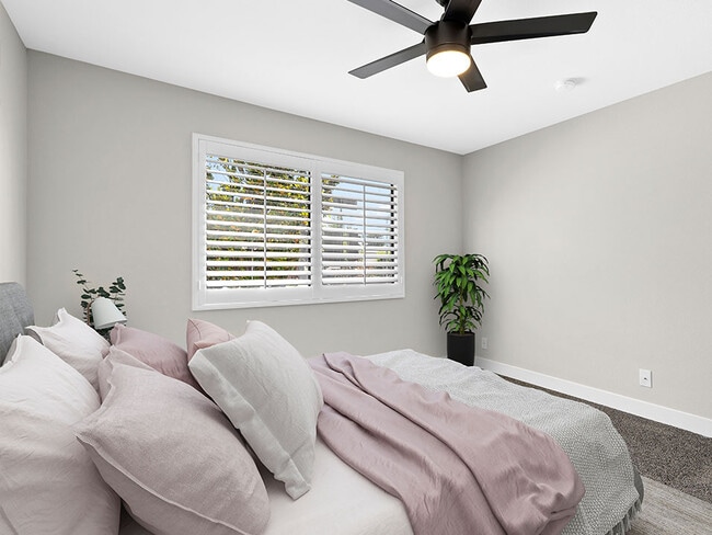 Carpeted bedroom with ceiling fan and large windows.