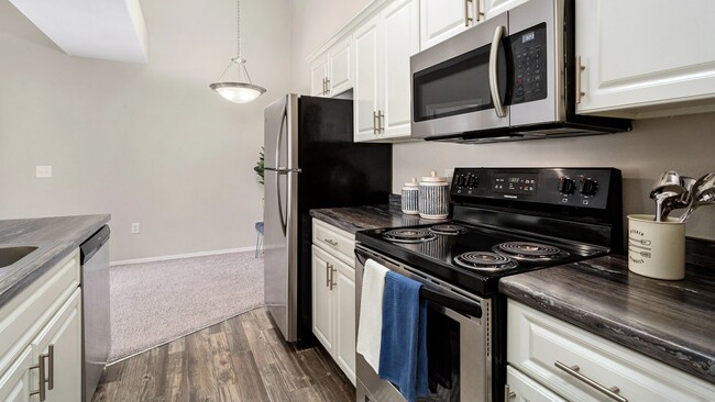 Our signature style floor plans feature kitchens with stainless steel appliances, white cabinetry and wood-style flooring. - Riverwood Apartments