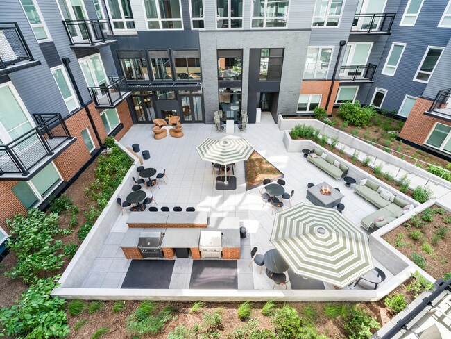 Interior courtyard with lounge seating, café tables, and grilling stations arranged around landscaped planters for shared outdoor time.