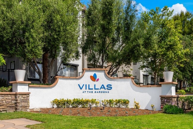 Villas acogedoras en los jardines. Señalización rodeada de árboles y flores.